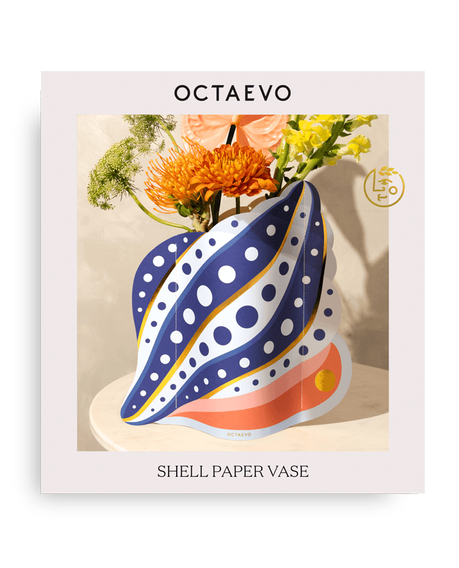 Octaevos Shell Paper Vase with polka dots sits on a table, holding orange and yellow flowers.