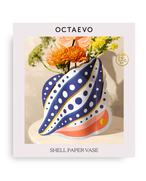 Octaevos Shell Paper Vase with polka dots sits on a table, holding orange and yellow flowers.