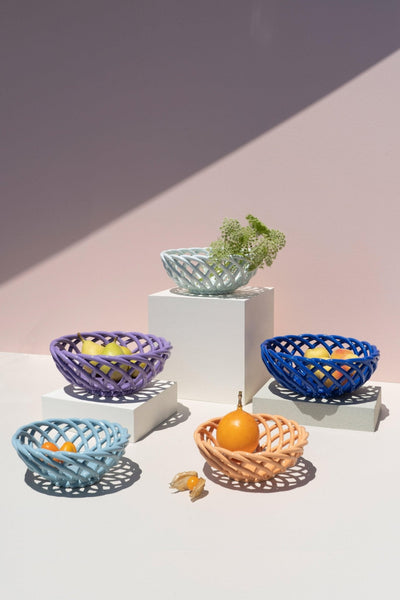 The OCTAEVO Sicilia Ceramic Basket displays fruit and greenery on white blocks with a light pink background and shadow.