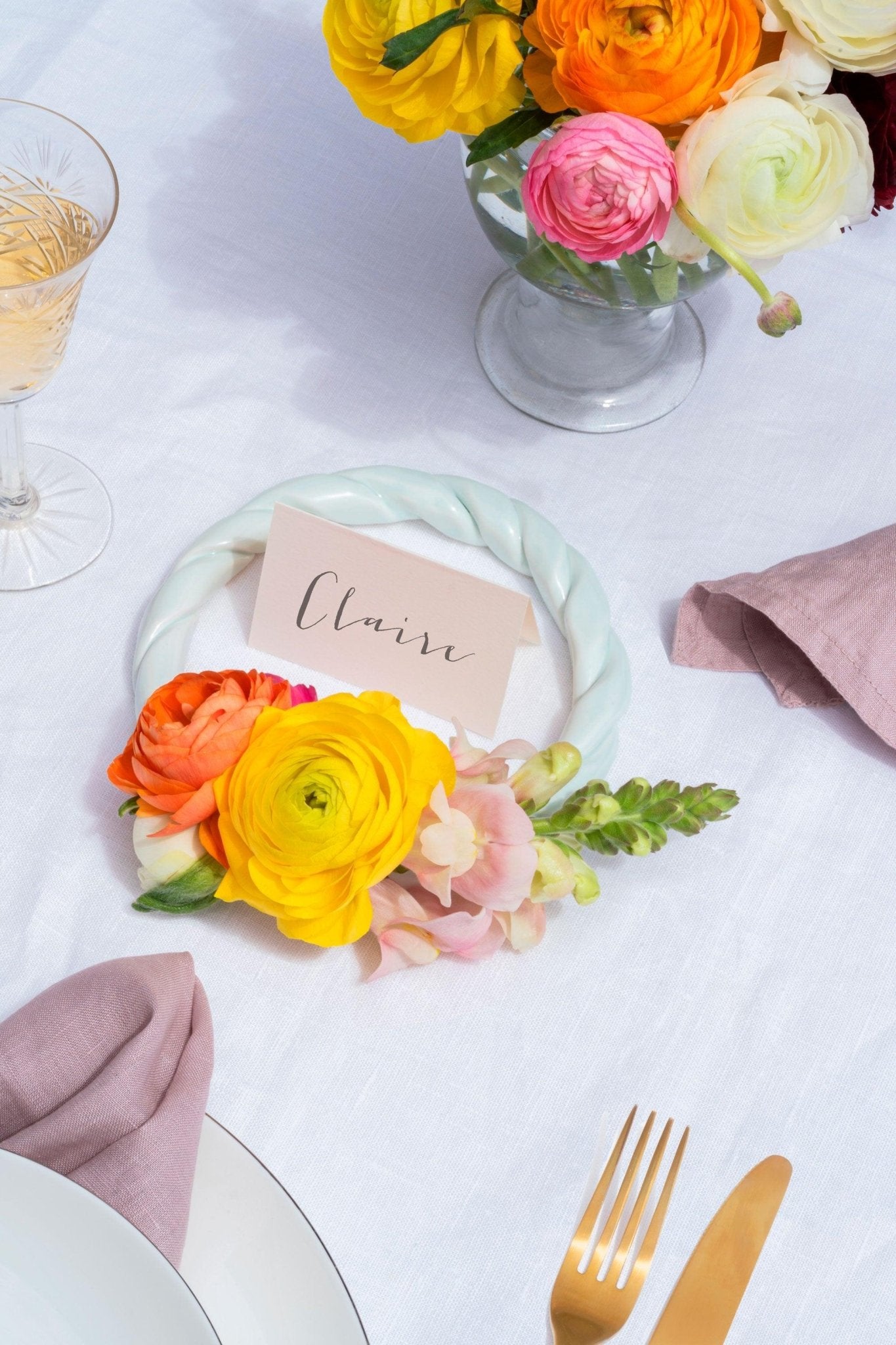 A place card reading Claire with bright flowers, gold cutlery, and the light mint OCTAEVO Sicilia Ceramic Trivet as table decor.