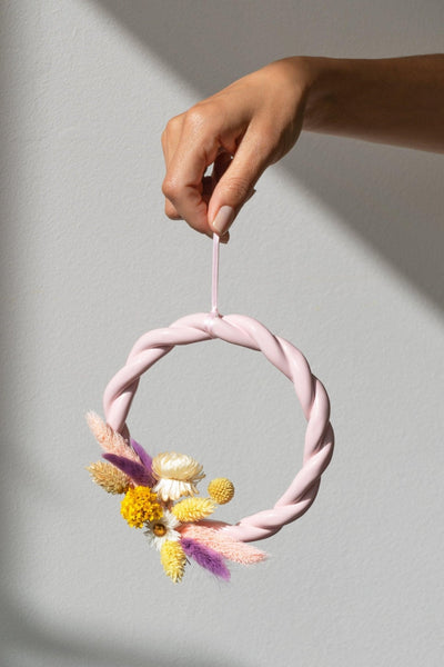 A hand holds the pink OCTAEVO Sicilia Ceramic Trivet, perfect as earthenware wall decor against a light gray background.
