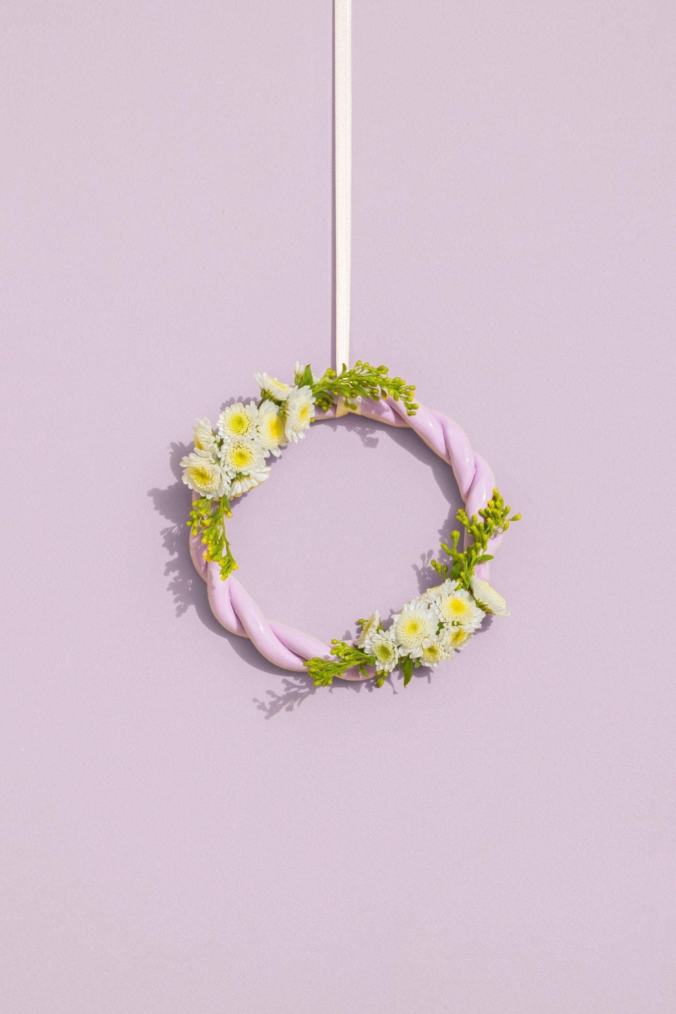 The purple OCTAEVO Sicilia Ceramic Trivet is displayed on a wall, adding a decorative pastel touch.