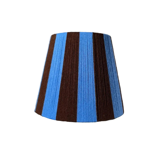 A Slice Shades handmade yarn striped lampshade with alternating vertical stripes of blue and dark brown, displayed on a white fabric backdrop.

