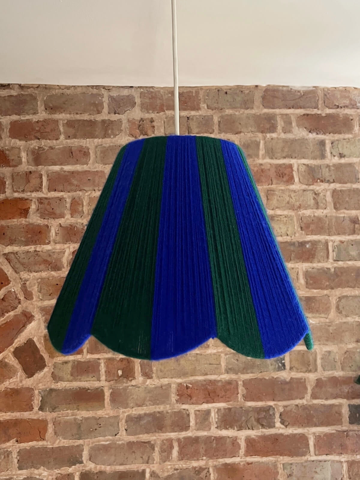 A Slice Shades handwoven yarn striped Scallop Lampshade in the sun in Cobalt Blue & Emerald Green.
