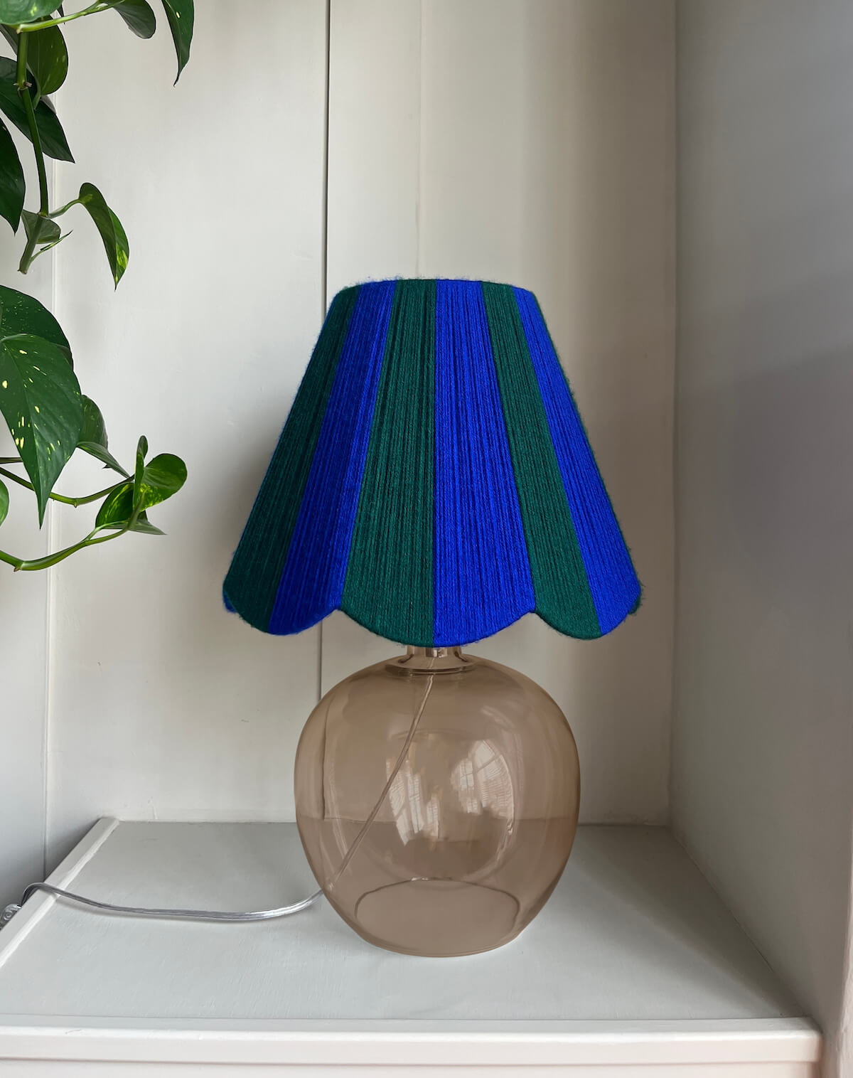 A Slice Shades handwoven yarn striped Scallop Lampshade in the sun in Cobalt Blue & Emerald Green.
