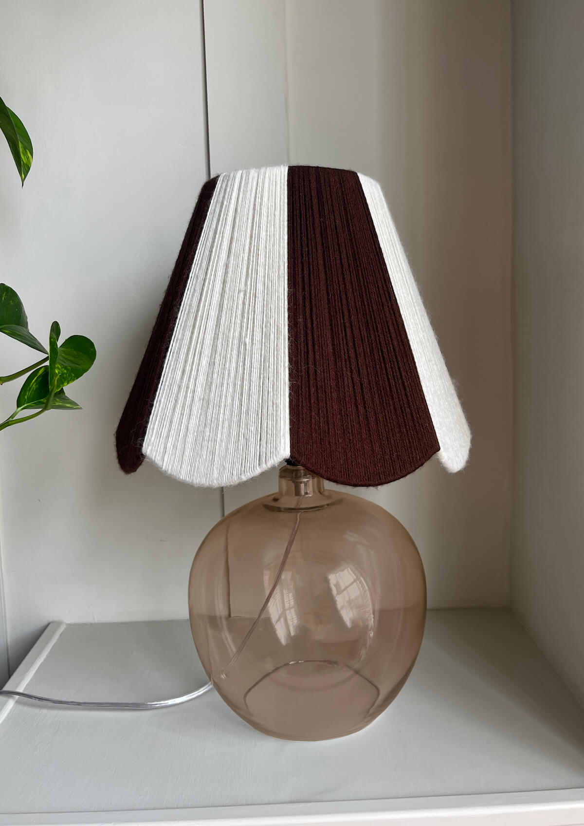A handmade yarn scallop lampshade by Slice Shades in Ecru and Cocoa white and brown.