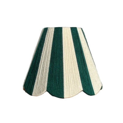 A Slice Shades handwoven yarn string striped lampshade in emerald green and ecru. A festive candy cane shade sitting on a natural bench with shadows in sunlight.