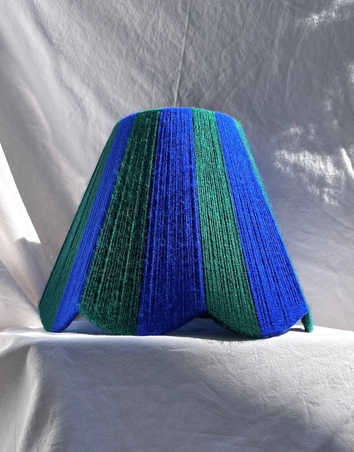 A Slice Shades handwoven yarn striped Scallop Lampshade in the sun in Cobalt Blue & Emerald Green.