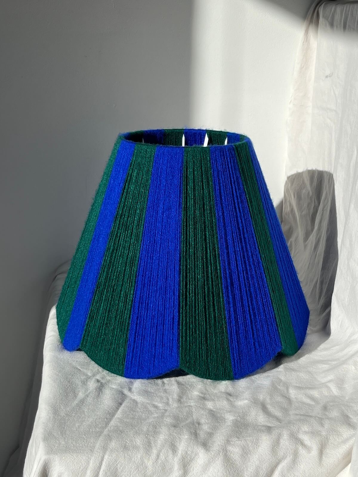 A Slice Shades handwoven yarn striped Scallop Lampshade in the sun in Cobalt Blue & Emerald Green.