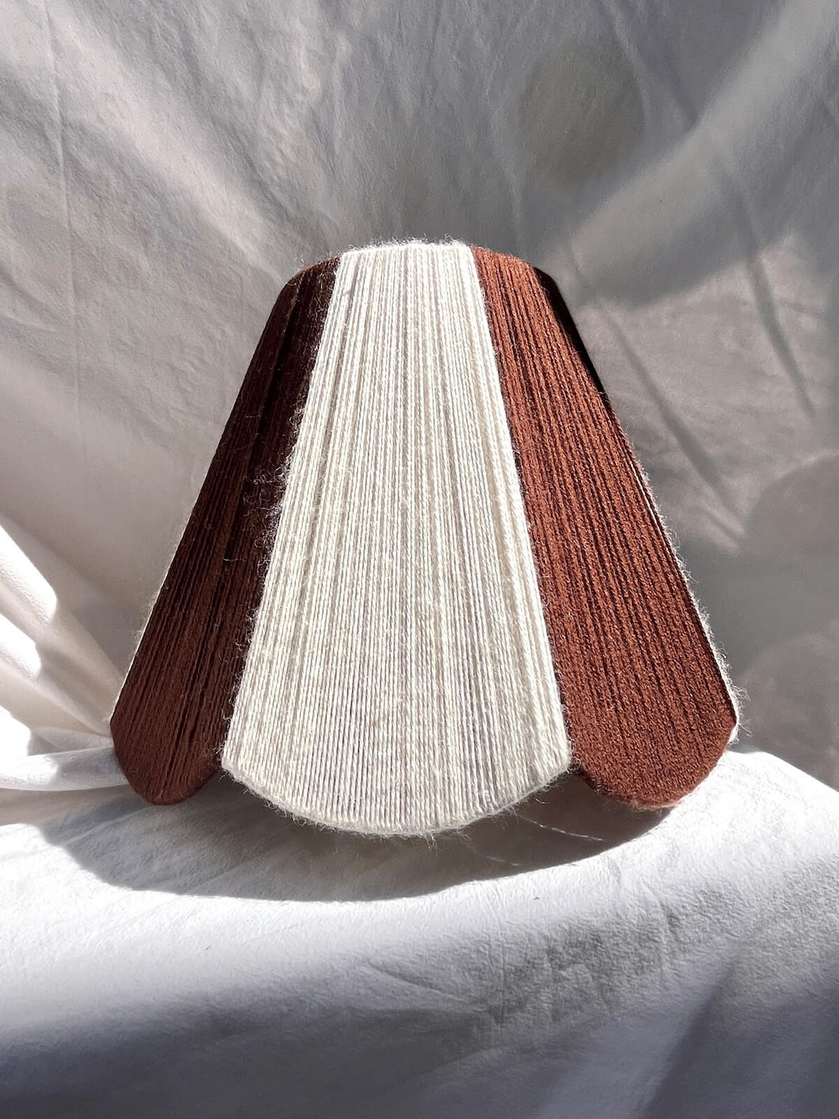 A handmade yarn scallop lampshade by Slice Shades in Ecru and Cocoa white and brown.