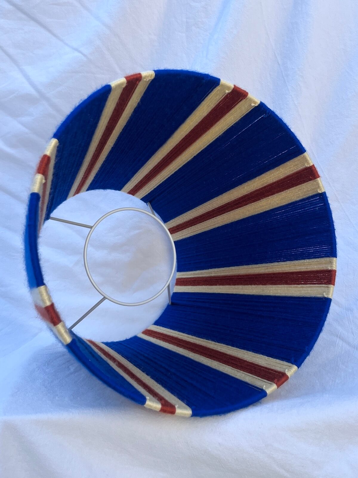 A Slice Shades handwoven striped yarn lampshade in cobalt blue, butter yellow and burnt orange stripes.