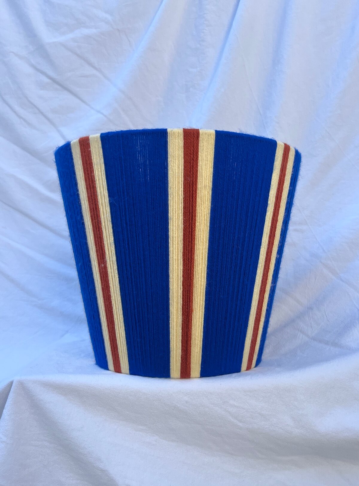 A Slice Shades handwoven striped yarn lampshade in cobalt blue, butter yellow and burnt orange stripes.
