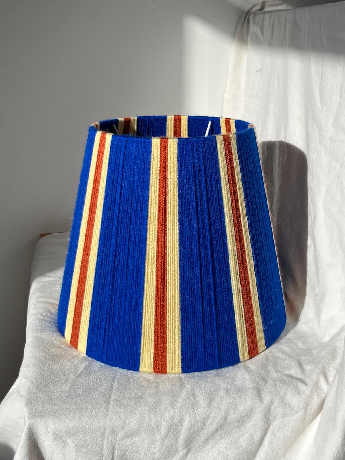 A Slice Shades handwoven striped yarn lampshade in cobalt blue, butter yellow and burnt orange stripes.