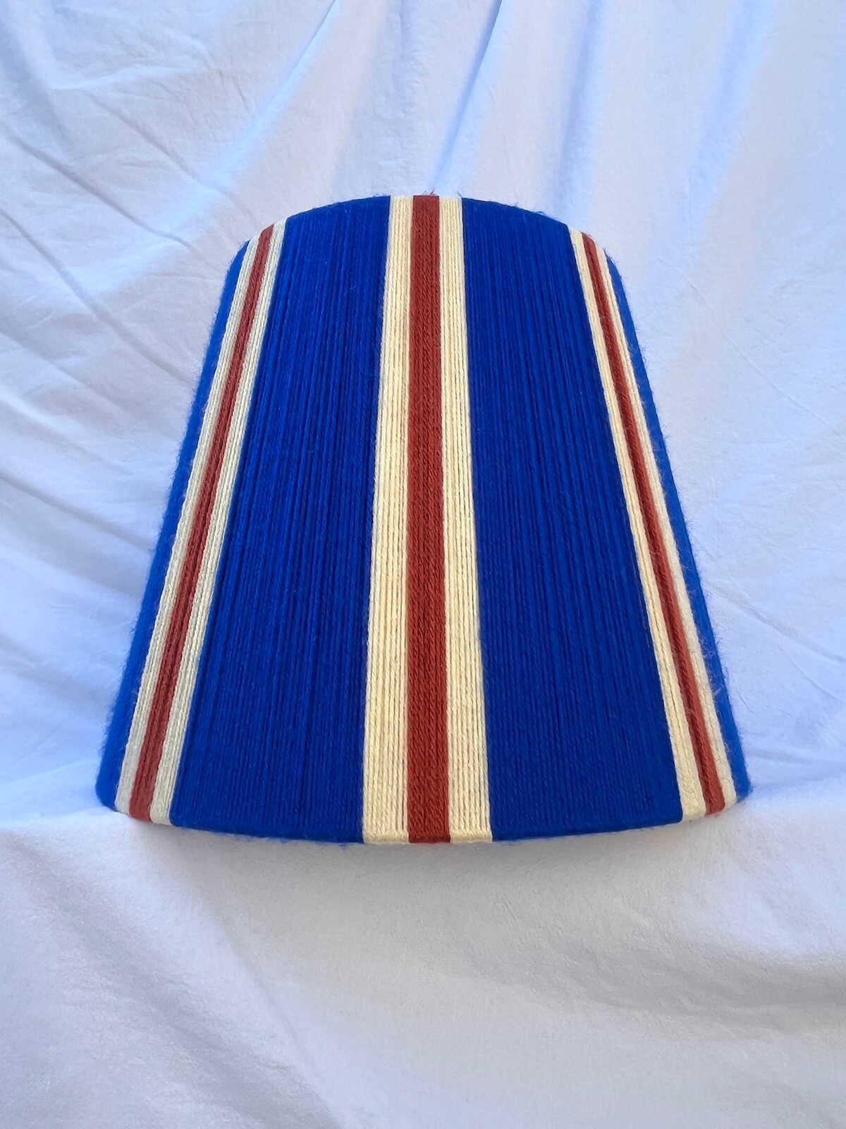 A Slice Shades handwoven striped yarn lampshade in cobalt blue, butter yellow and burnt orange stripes.