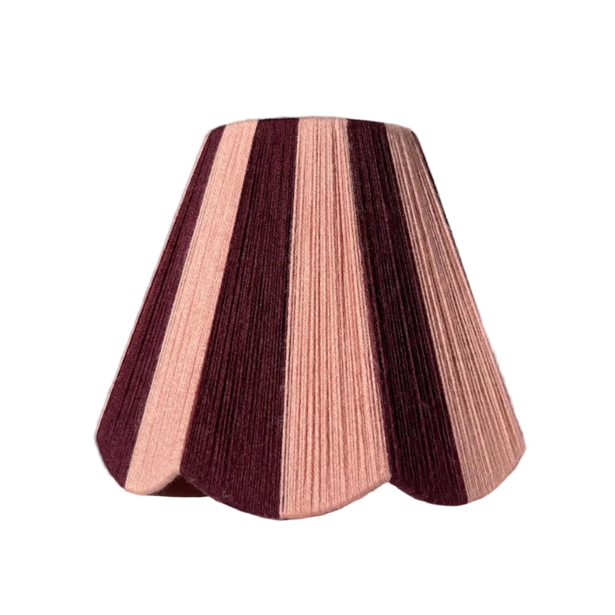 A Slice Shades handwoven yarn lampshade with vertical stripes in dusty pink  and deep burgundy, set against a draped white fabric background.