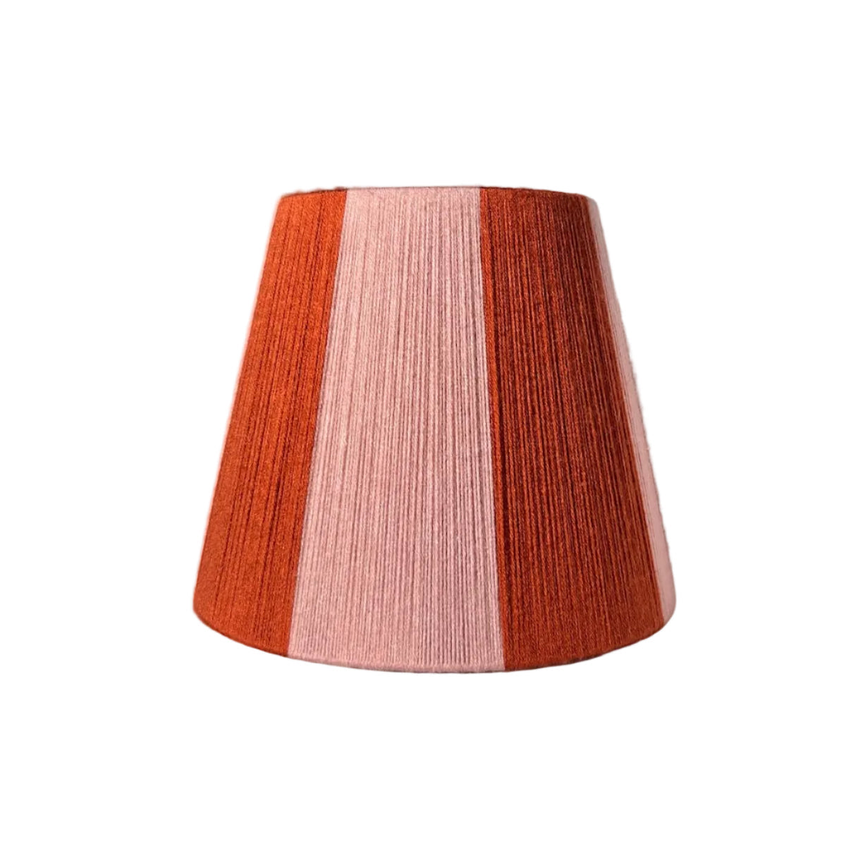 A Slice Shades handwoven yarn striped lampshade with vertical stripes in rust orange and light pink, photographed against a wrinkled white fabric backdrop.