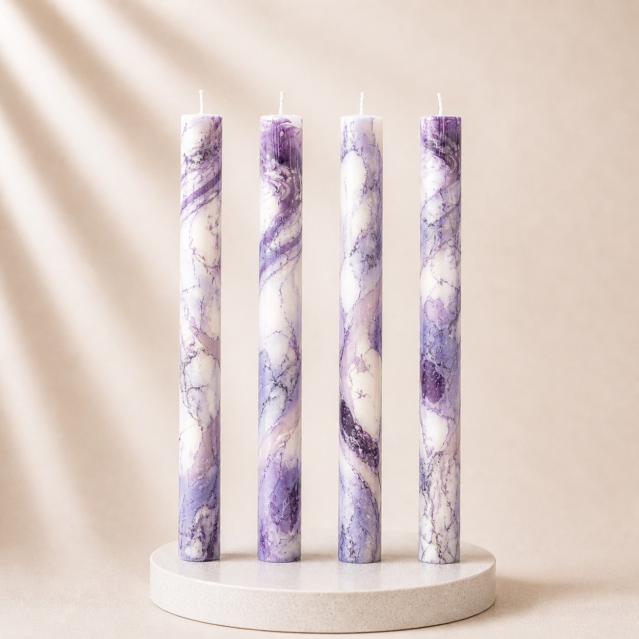 Four purple marbled candles on a white stand against a beige background