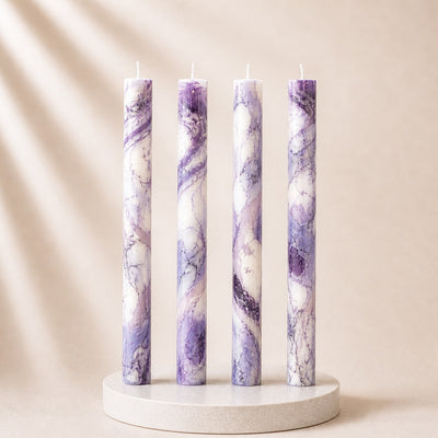 Four purple marbled candles on a white stand against a beige background