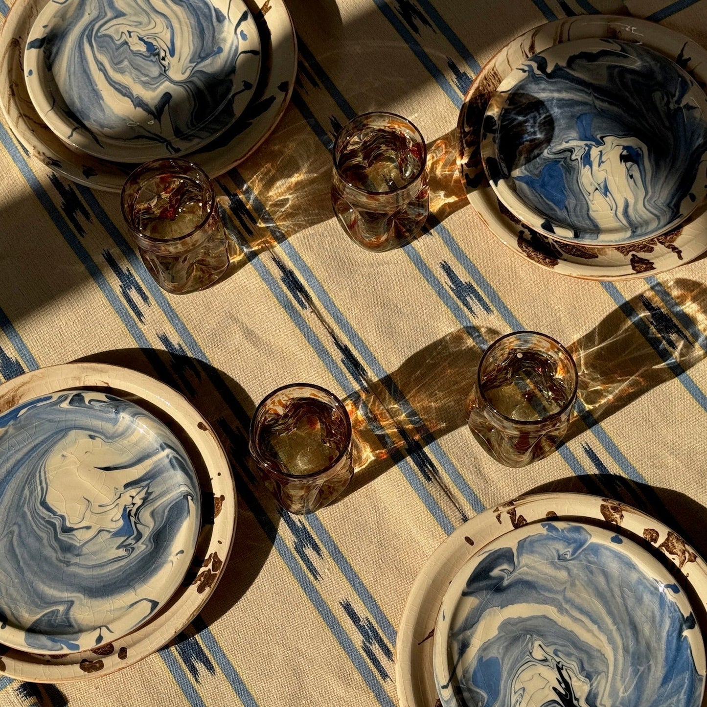 Decorative ceramic plates with blue and white marbled design on a striped surface - lifestyle