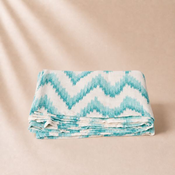 Folded blanket with blue and white zigzag pattern on a beige background