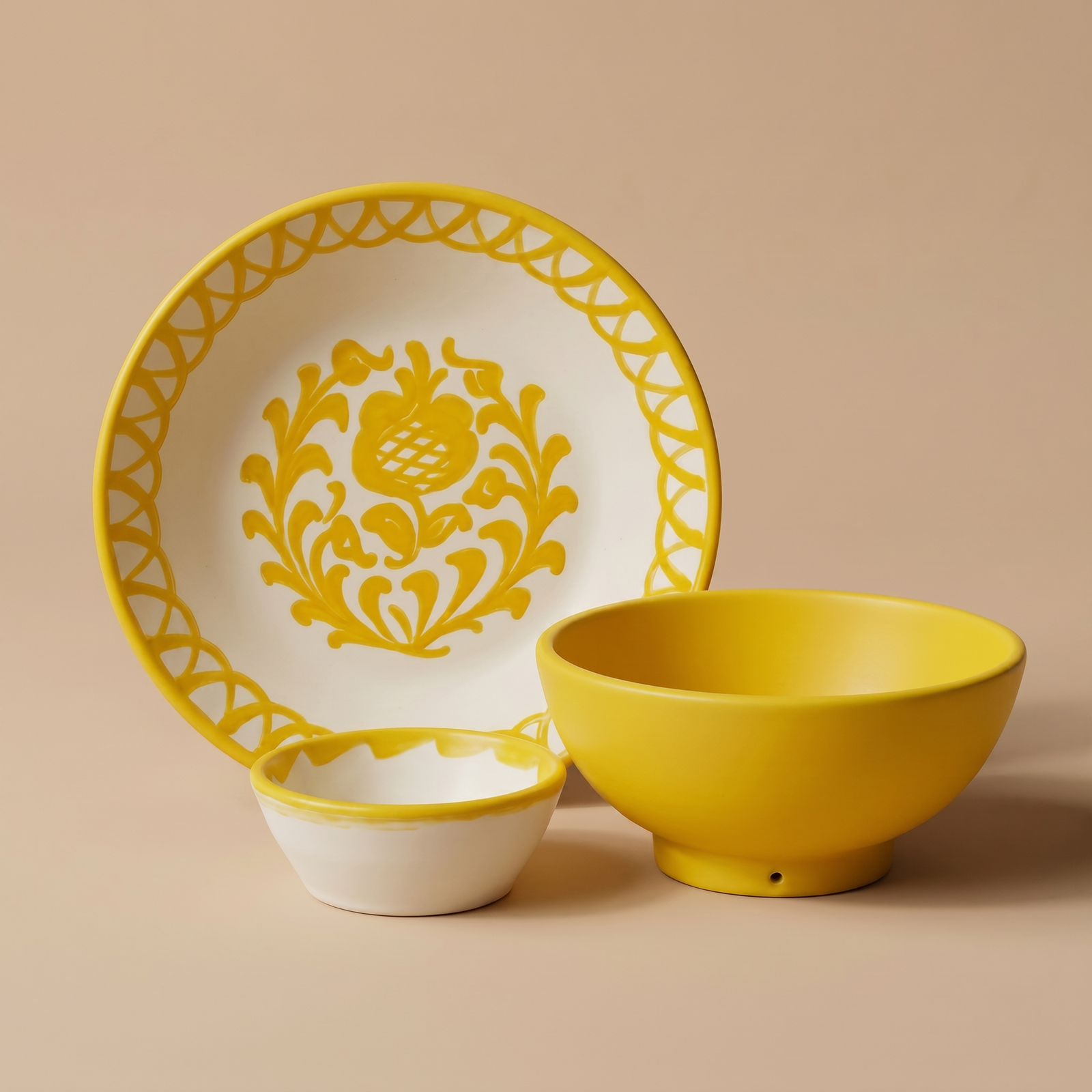 Ceramic plate, bowl, and saucer with yellow floral design on a beige background