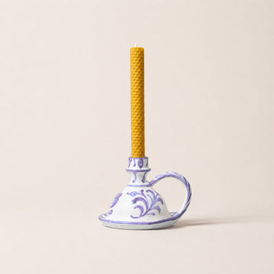 Yellow candle in a decorative ceramic holder on a beige background