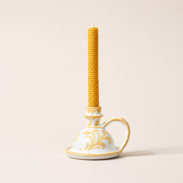 Decorative candle holder with a textured yellow candle on a beige background