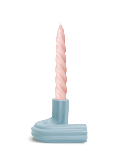 A pastel pink twisted candle in Light BlueTemplo Candle Holder by OCTAEVO set against a plain white background.