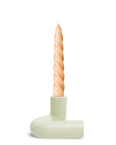 A twisted beige candle stands upright in OCTAEVO’s Templo Candle Holder, in Light Mint L-shaped chamberstick.