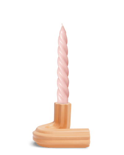 A pink spiral candle sits in Orange OCTAEVO Templo Candle Holder, a peach ceramic piece, against a white background.