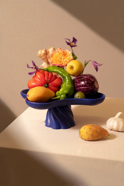 Colorful fruits and veggies on the Octaevo Templo High Tray in blue, with garlic and prickly pear beside the blue centerpiece