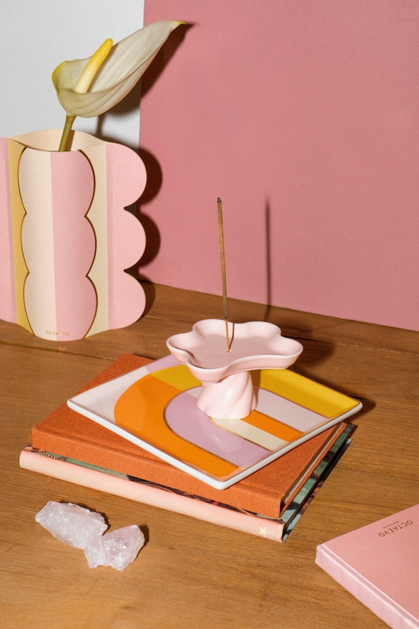 A modern pink setup with Octaevo’s Templo Incense Holder, books, and crystals on a wooden table.