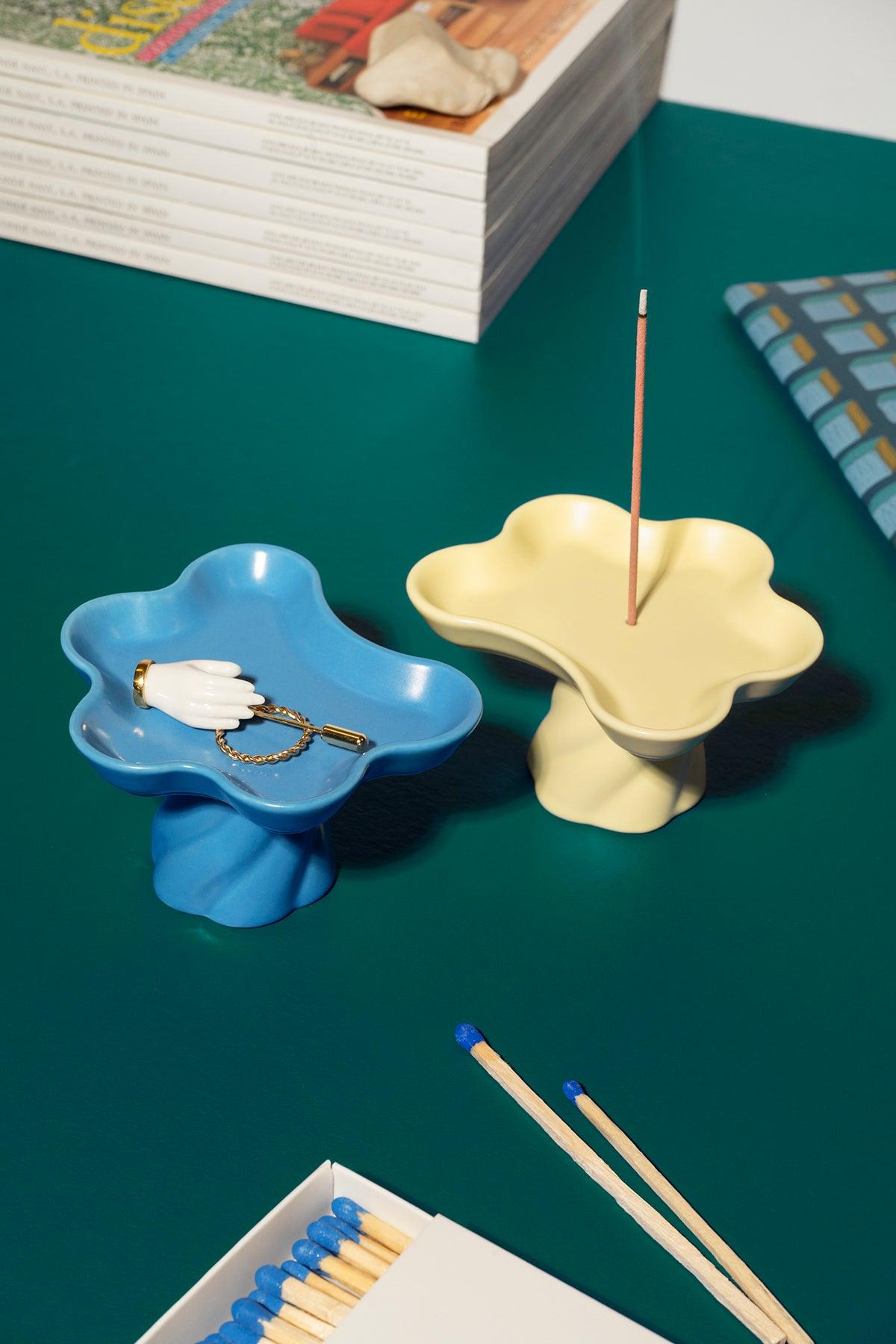 The Octaevo Templo Incense Holder in blue doubles as a decorative flower-shaped tray and incense holder on a green table.