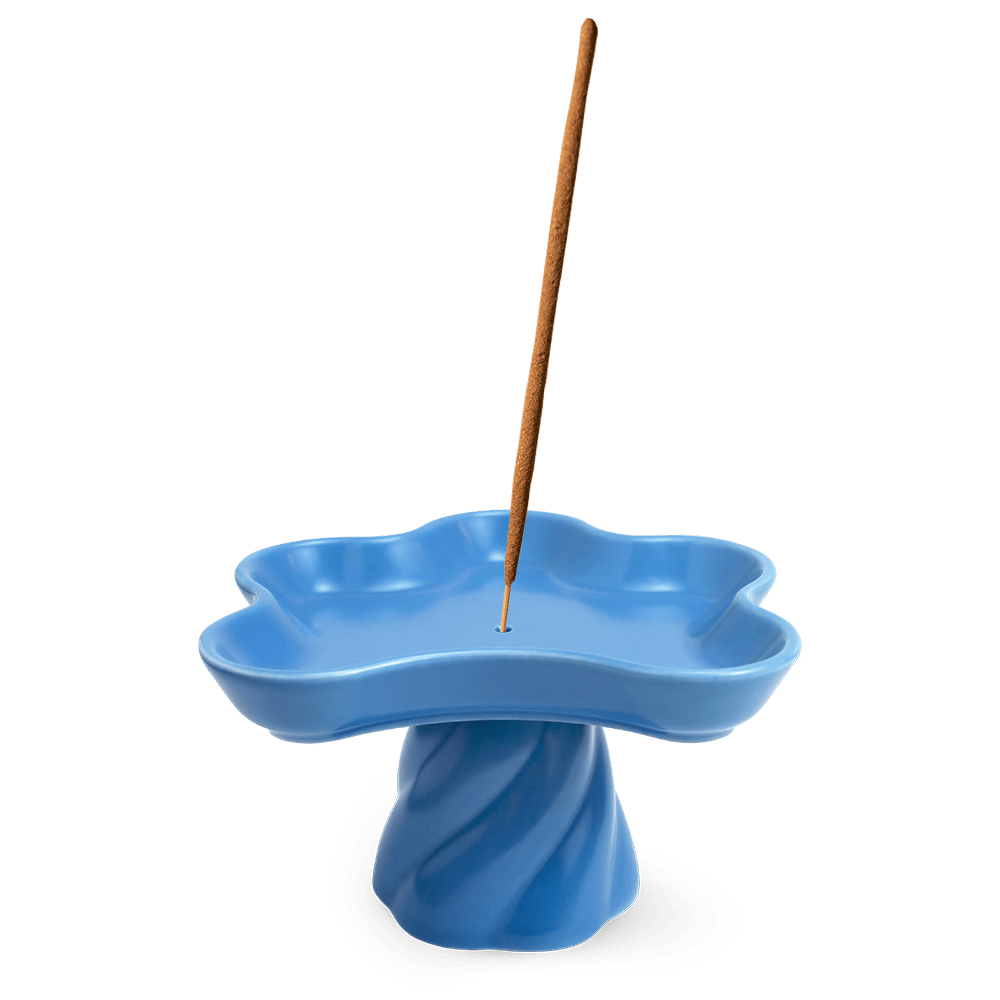 The Templo Incense Holder by OCTAEVO is a blue, flower-shaped stoneware piece with an upright incense stick.