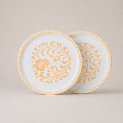 Two decorative plates with gold floral patterns on a beige background