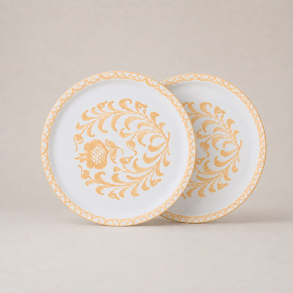 Two decorative plates with gold floral patterns on a beige background