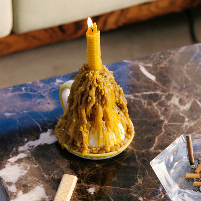 Burnt candle in a white cup on a marble surface with matches and an ashtray. - lifestyle