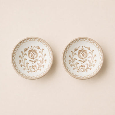 Two decorative ceramic bowls with floral patterns on a beige background