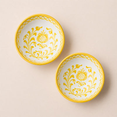 Two yellow-trimmed ceramic bowls with floral patterns on a beige background