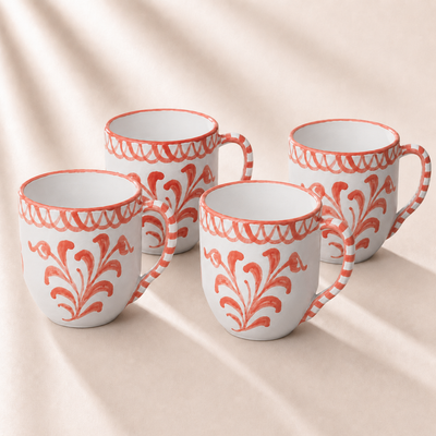 Four white mugs with orange floral patterns on a beige background