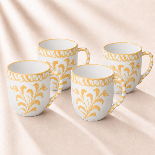 Four white mugs with yellow floral patterns on a beige fabric background