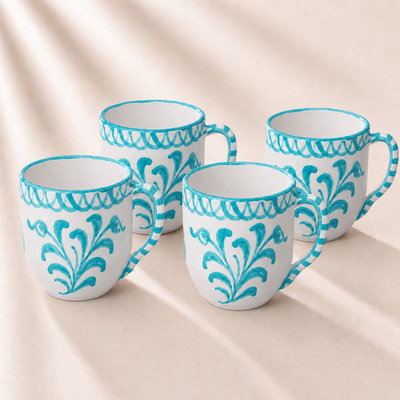 Four ceramic mugs with turquoise decorative patterns on a beige background