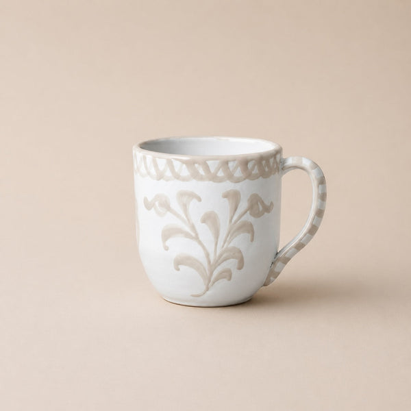 White ceramic mug with decorative floral pattern on a beige background
