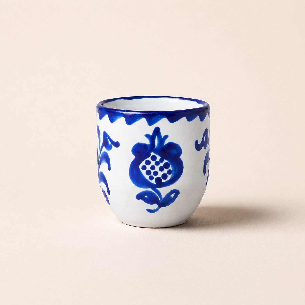 Ceramic cup with blue floral patterns on a beige background