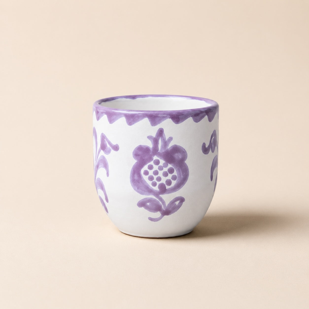 Ceramic cup with purple floral patterns on a beige background