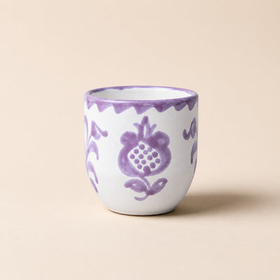 Ceramic cup with purple floral patterns on a beige background