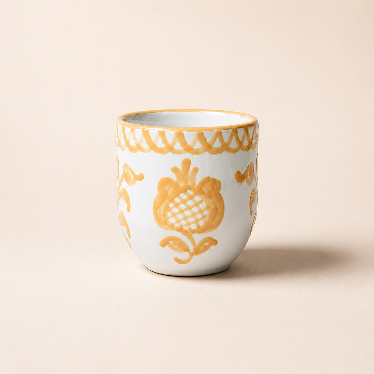 White ceramic cup with yellow floral patterns on a beige background