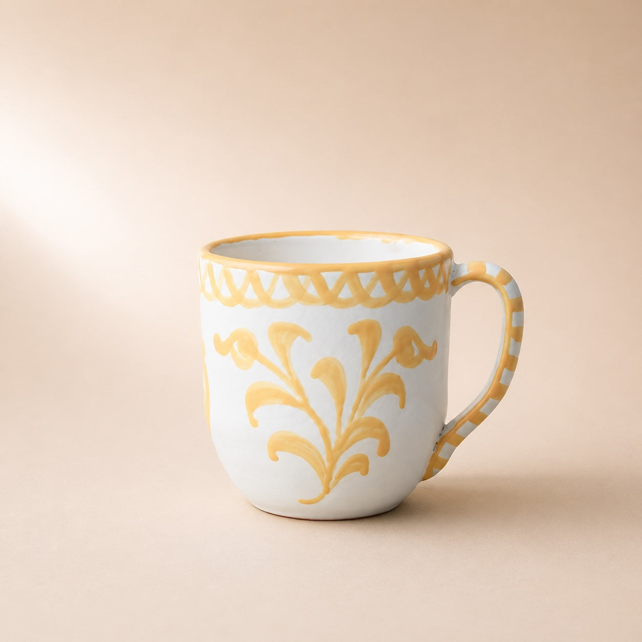 White mug with yellow floral patterns on a beige background