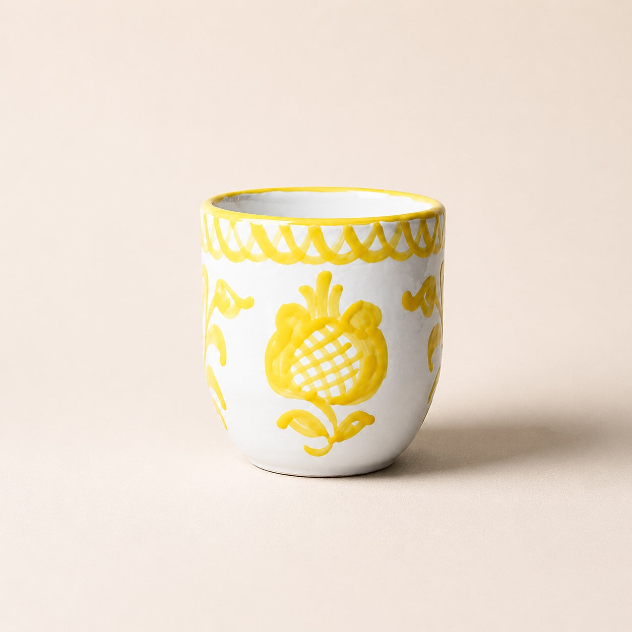 White ceramic cup with yellow floral patterns on a beige background