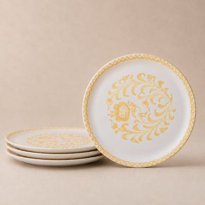Set of white plates with gold decorative patterns on a beige background